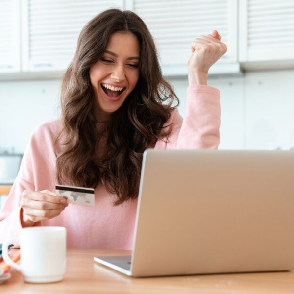 Person celebrating in front of laptop after winning online auction