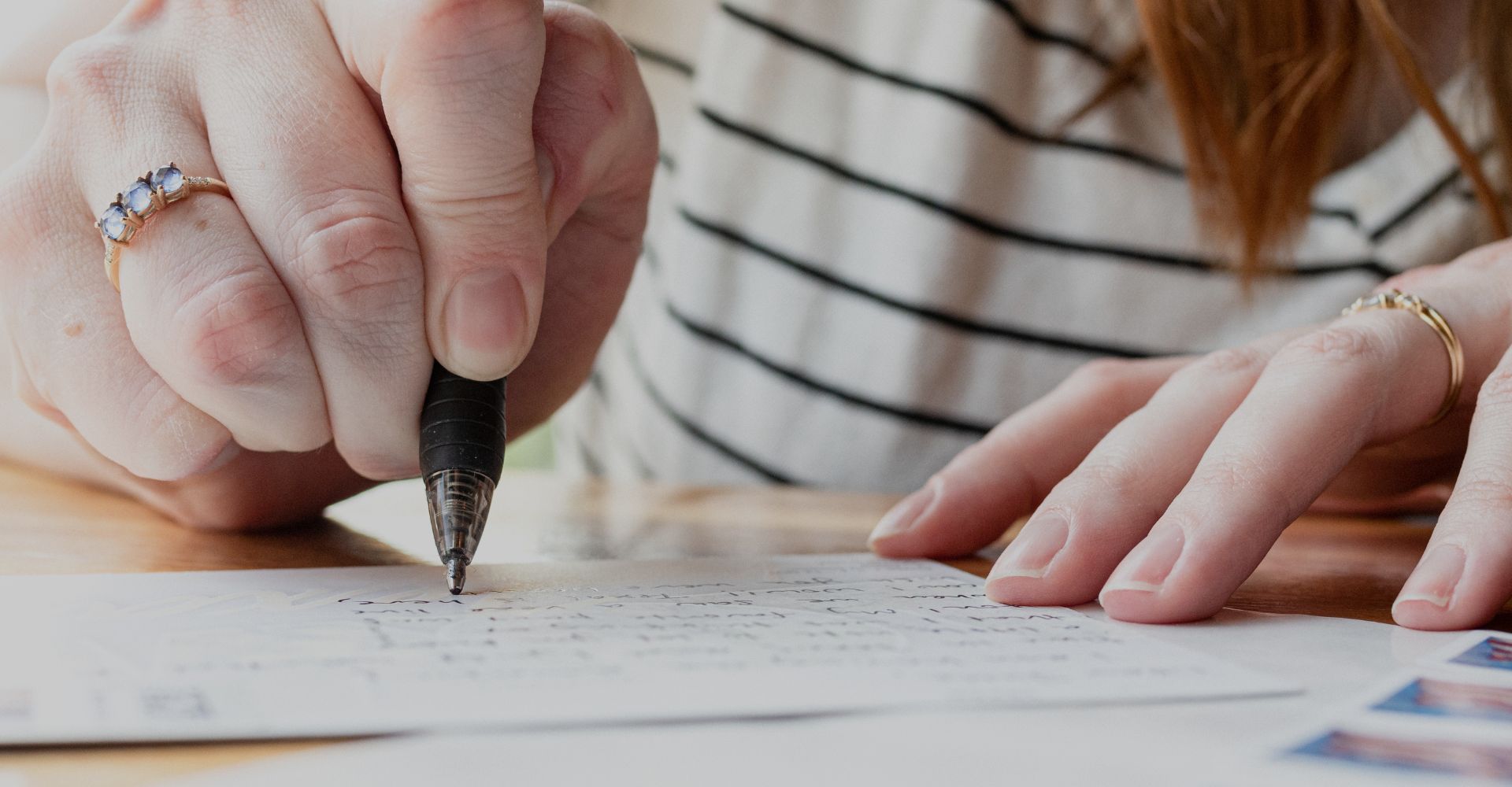 A person writing on a postcard